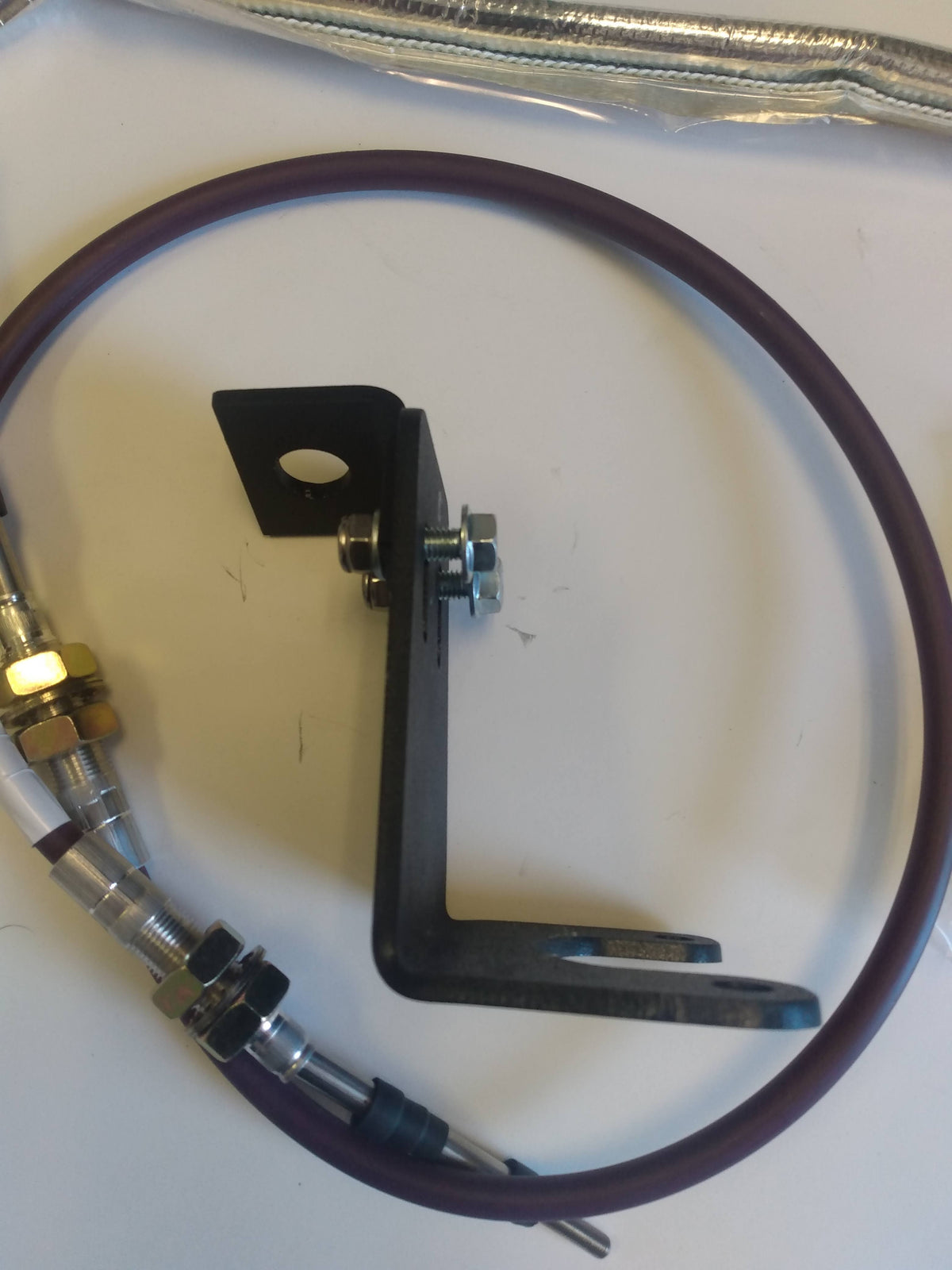 Wicked Wrench Motorsports structural 316 steel reinforcement bracket sitting next to the heavy duty 4WD shifter cable upgrade kit hardware