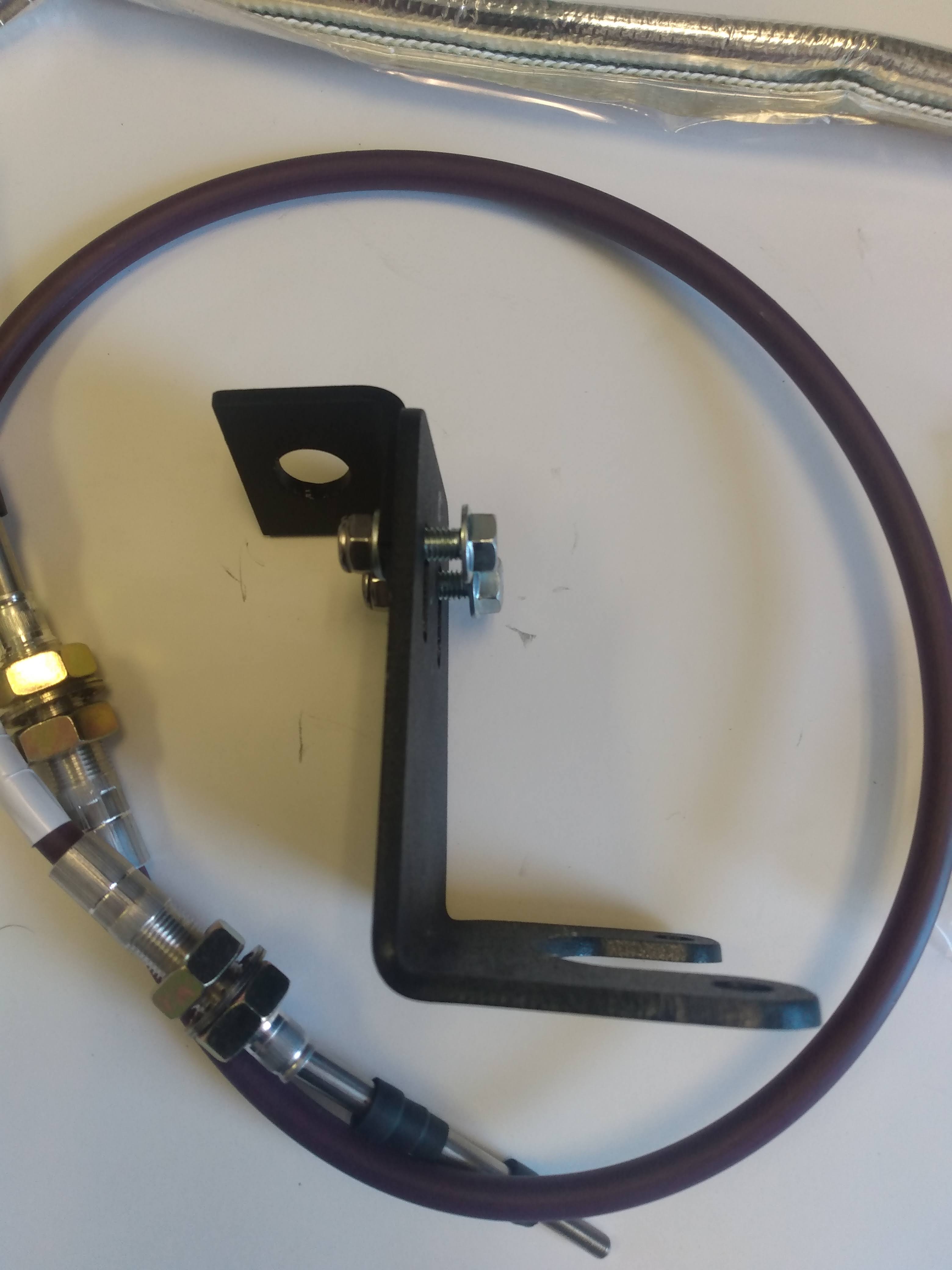 Wicked Wrench Motorsports structural 316 steel reinforcement bracket sitting next to the heavy duty 4WD shifter cable upgrade kit hardware