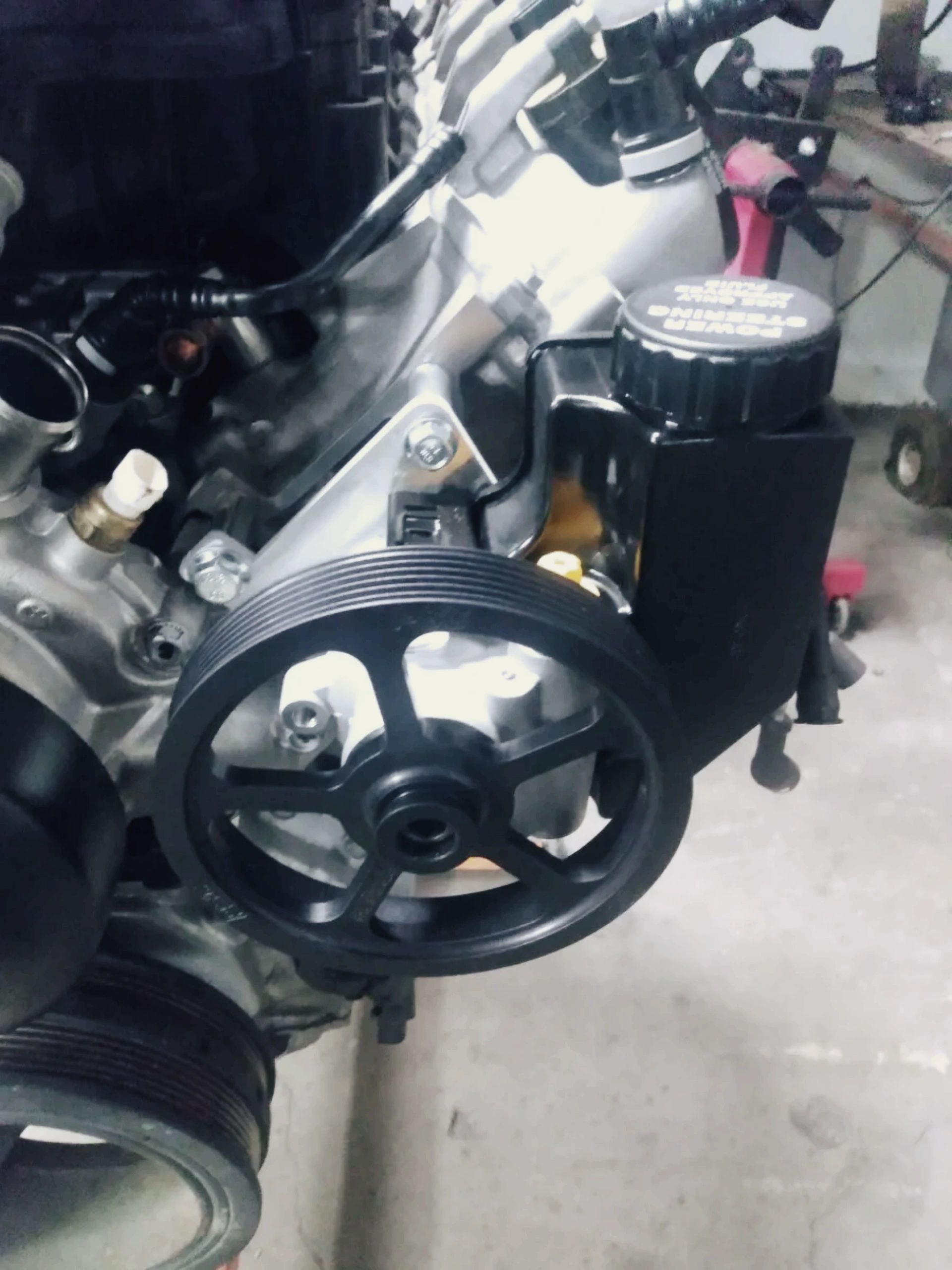 Close up view of the Wicked Wrench Motorsports Type II power steering pump pulley and custom mounting bracket installed on a Gen V LT engine